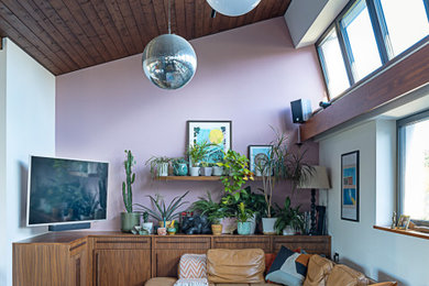 Photo of a medium sized retro open plan living room in London with pink walls, a wall mounted tv, black floors, a timber clad ceiling and feature lighting.