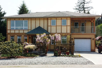Design ideas for a mid-sized arts and crafts two-storey stucco yellow house exterior in Vancouver with a hip roof and a shingle roof.