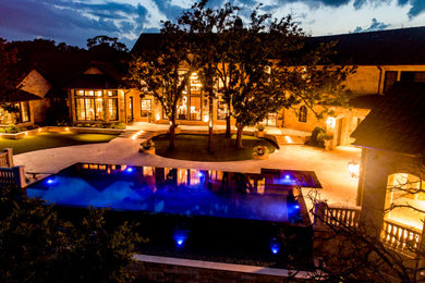 Imagen de piscina infinita campestre grande a medida en patio trasero con adoquines de piedra natural