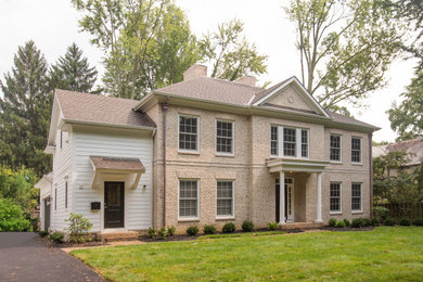 Example of a large classic beige two-story brick and clapboard exterior home design in Columbus with a shingle roof and a brown roof