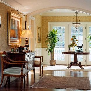 Inspiration för stora klassiska hallar, med gula väggar och mellanmörkt trägolv