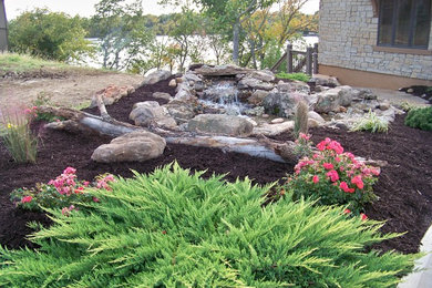 This is an example of a mid-sized rustic full sun side yard mulch water fountain landscape in Kansas City.