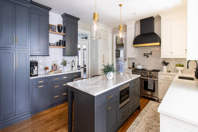 Inspiration for a large transitional u-shaped medium tone wood floor and brown floor enclosed kitchen remodel in Philadelphia with an undermount sink, recessed-panel cabinets, gray cabinets, marble countertops, white backsplash, glass tile backsplash, stainless steel appliances, an island and white countertops