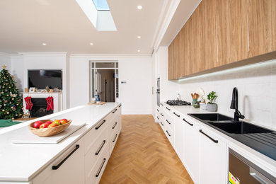 Design ideas for a large contemporary kitchen in Adelaide with a double-bowl sink, shaker cabinets, white cabinets, quartz benchtops, white splashback, cement tile splashback, stainless steel appliances, light hardwood floors, with island, brown floor and white benchtop.