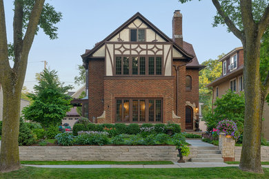 Small transitional three-storey brick brown house exterior in Milwaukee with a shingle roof.