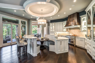 Inspiration for a large traditional single-wall open plan kitchen in Indianapolis with a farmhouse sink, flat-panel cabinets, white cabinets, white splashback, panelled appliances, dark hardwood floors, multiple islands, brown floor and white benchtop.