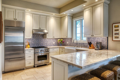 Example of a transitional travertine floor and beige floor kitchen design in Other with a farmhouse sink, quartzite countertops, blue backsplash, ceramic backsplash and stainless steel appliances