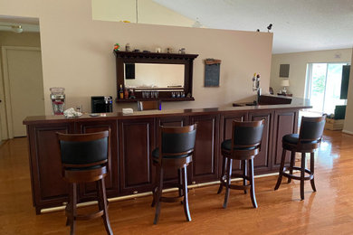 Inspiration for a large contemporary l-shaped seated home bar remodel in Miami with a drop-in sink, raised-panel cabinets, red cabinets, wood countertops, red backsplash, wood backsplash and red countertops