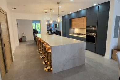 Large minimalist porcelain tile and gray floor kitchen photo in Miami with an undermount sink, flat-panel cabinets, blue cabinets, quartz countertops, beige backsplash, quartz backsplash, paneled appliances, an island and beige countertops