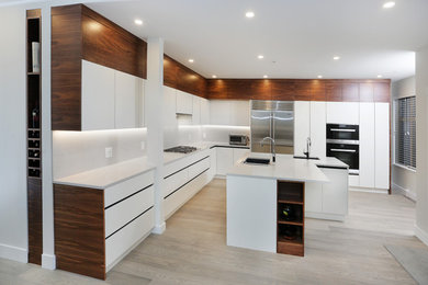 Photo of a large modern l-shaped open plan kitchen in Vancouver with flat-panel cabinets, white cabinets, quartz benchtops, white splashback, cement tile splashback, stainless steel appliances, light hardwood floors, beige floor, an undermount sink, a peninsula and white benchtop.