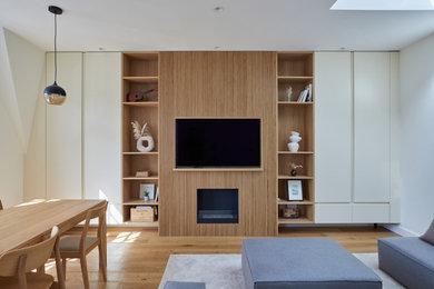 Exemple d'un salon de taille moyenne et ouvert avec un mur blanc, un sol en bois brun, une cheminée ribbon, un manteau de cheminée en lambris de bois, un téléviseur encastré, un sol marron et éclairage.