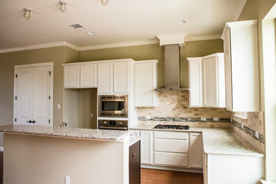 Inspiration for a mid-sized transitional l-shaped medium tone wood floor eat-in kitchen remodel in Austin with an undermount sink, recessed-panel cabinets, white cabinets, granite countertops, beige backsplash, stone tile backsplash, stainless steel appliances and an island