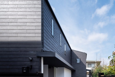 Exempel på ett stort modernt svart hus, med två våningar, fiberplattor i betong, pulpettak och tak i metall