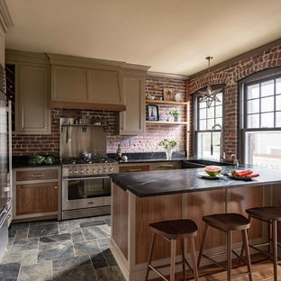 Свежая идея для дизайна: угловая кухня в стиле кантри с кладовкой, врезной раковиной, фасадами в стиле шейкер, коричневыми фасадами, красным фартуком, фартуком из кирпича, техникой из нержавеющей стали, полом из сланца, островом, разноцветным полом и черной столешницей - отличное фото интерьера