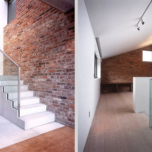 This is an example of a large modern concrete curved metal railing staircase in Hertfordshire with glass risers.