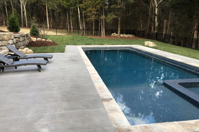 Diseño de piscinas y jacuzzis naturales actuales grandes rectangulares en patio trasero con losas de hormigón