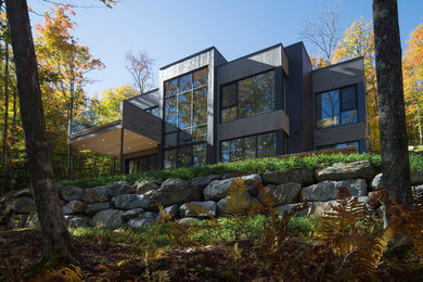 This is an example of a mid-sized contemporary two-storey grey exterior in Montreal with wood siding and a flat roof.