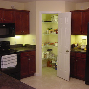 Traditional kitchen pantry remodeling - Elegant l-shaped kitchen pantry photo in Bridgeport with a double-bowl sink, recessed-panel cabinets, dark wood cabinets, laminate countertops and black appliances