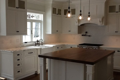 Inspiration for a large rustic l-shaped medium tone wood floor and brown floor enclosed kitchen remodel in New York with a farmhouse sink, recessed-panel cabinets, white cabinets, white backsplash, subway tile backsplash and an island