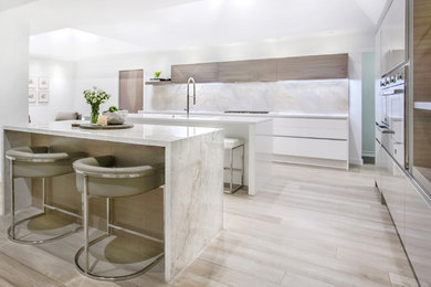 Inspiration for a large contemporary l-shaped open plan kitchen in Dallas with an undermount sink, flat-panel cabinets, white cabinets, marble benchtops, beige splashback, marble splashback, stainless steel appliances, light hardwood floors, multiple islands and beige floor.