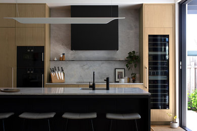 Contemporary galley open plan kitchen in Perth with a single-bowl sink, flat-panel cabinets, light wood cabinets, marble benchtops, grey splashback, marble splashback, black appliances, light hardwood floors, with island and grey benchtop.