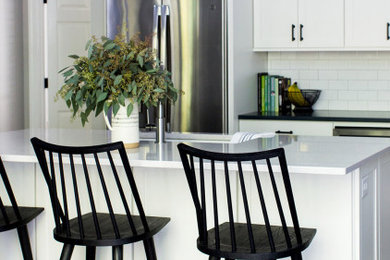 Transitional dark wood floor and brown floor eat-in kitchen photo in Raleigh with shaker cabinets, white cabinets, quartz countertops, white backsplash, stainless steel appliances and an island