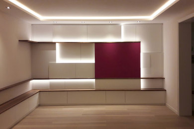 Diseño de sala de estar abierta contemporánea grande con paredes blancas, suelo de madera clara, televisor retractable y suelo marrón