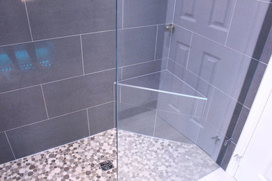Mid-sized minimalist kids' beige tile and porcelain tile porcelain tile alcove shower photo in Toronto with a one-piece toilet, gray walls, a wall-mount sink and solid surface countertops