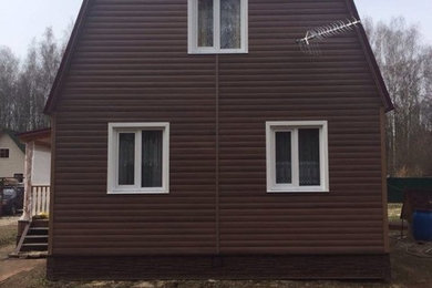 На фото: двухэтажный, коричневый частный загородный дом среднего размера с облицовкой из винила, двускатной крышей и металлической крышей