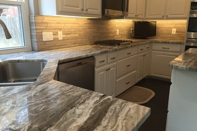 Elegant u-shaped kitchen photo in Houston with an undermount sink, raised-panel cabinets, white cabinets, marble countertops, brown backsplash, porcelain backsplash, stainless steel appliances and an island