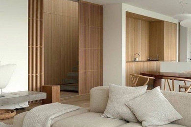 Diseño de salón abierto minimalista grande sin chimenea con paredes blancas, suelo de madera clara y suelo marrón