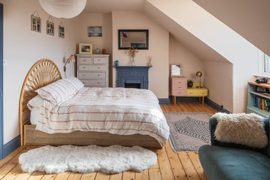 Inspiration for a bohemian bedroom in Other with pink walls, medium hardwood flooring, brown floors and a standard fireplace.