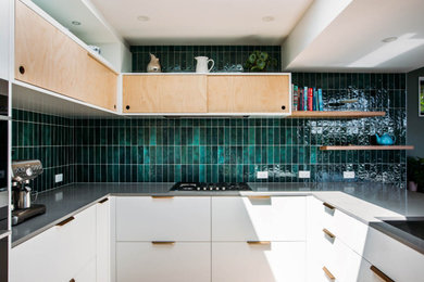 Inspiration for a mid-sized eclectic galley eat-in kitchen in Wellington with an undermount sink, granite benchtops, green splashback, ceramic splashback, black appliances, a peninsula and grey benchtop.