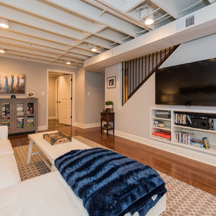 Imagen de sótano con ventanas clásico, grande, sin chimenea, con paredes grises y suelo de madera oscura