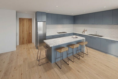 Inspiration for a l-shaped open plan kitchen in London with a double-bowl sink, blue cabinets, marble worktops, white splashback, ceramic splashback, stainless steel appliances, laminate floors, an island, brown floors and white worktops.