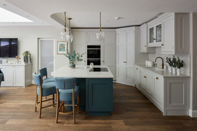 Idéer för ett mellanstort klassiskt grå kök med öppen planlösning, med en integrerad diskho, skåp i shakerstil, blå skåp, bänkskiva i kvartsit, grått stänkskydd, svarta vitvaror, klinkergolv i porslin, en köksö och brunt golv