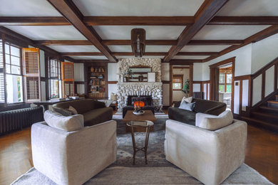 Example of a huge transitional formal and open concept medium tone wood floor, brown floor, coffered ceiling and wainscoting living room design in New York with a wood stove and a stone fireplace