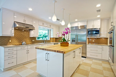 Example of a large trendy u-shaped ceramic tile eat-in kitchen design in Jacksonville with an undermount sink, flat-panel cabinets, white cabinets, wood countertops, subway tile backsplash, stainless steel appliances, an island and beige backsplash