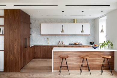 Design ideas for a mid-sized midcentury l-shaped separate kitchen in New York with an undermount sink, flat-panel cabinets, dark wood cabinets, solid surface benchtops, grey splashback, stone slab splashback, panelled appliances, light hardwood floors, a peninsula, beige floor and white benchtop.