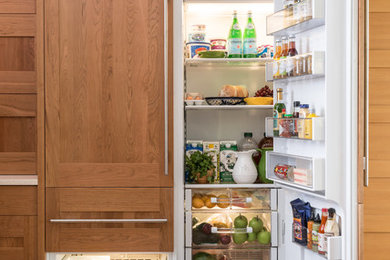 Example of a mid-sized transitional l-shaped medium tone wood floor eat-in kitchen design in Other with shaker cabinets, medium tone wood cabinets and paneled appliances
