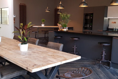 Design ideas for a large industrial grey and cream kitchen in Dorset with a built-in sink, flat-panel cabinets, grey cabinets, marble worktops, white splashback, light hardwood flooring, an island and black worktops.
