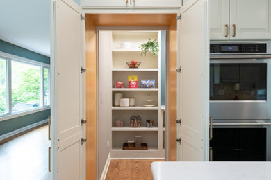 Example of a mid-sized transitional light wood floor and brown floor open concept kitchen design in Chicago with an undermount sink, shaker cabinets, white cabinets, quartz countertops, white backsplash, marble backsplash, stainless steel appliances, an island and white countertops