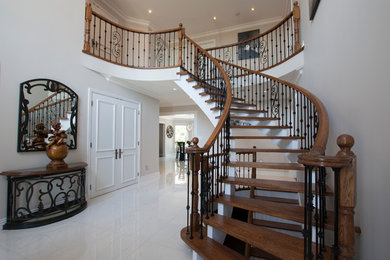 Mid-sized modern wood curved staircase in Toronto with open risers and wood railing.