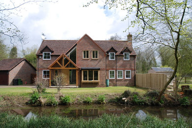 Mid-sized contemporary two-storey brick brown house exterior in Berkshire with a gable roof and a tile roof.