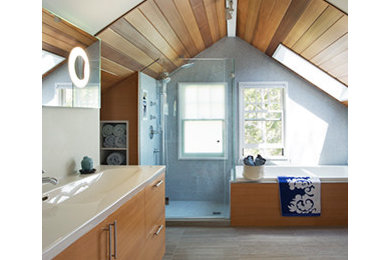 Photo of a mid-sized midcentury 3/4 bathroom in Boston with a trough sink, flat-panel cabinets, medium wood cabinets, solid surface benchtops, a drop-in tub, an open shower, a one-piece toilet, blue tile, mosaic tile and medium hardwood floors.