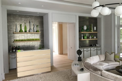 Example of a small minimalist single-wall light wood floor wet bar design in New York with an undermount sink, flat-panel cabinets, white cabinets, gray backsplash and metal backsplash