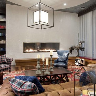 Medium sized modern home office and library in Minneapolis with a reading nook, white walls, medium hardwood flooring, a standard fireplace, a tiled fireplace surround, a built-in desk and brown floors.