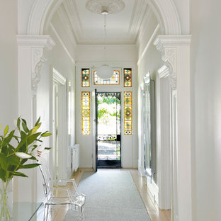 Foto di un corridoio chic con pareti bianche, parquet chiaro, una porta singola e una porta in metallo