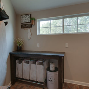 Inspiration for a small farmhouse utility room in Nashville with a belfast sink, shaker cabinets, brown cabinets, granite worktops, grey walls, brick flooring, a side by side washer and dryer, multi-coloured floors and black worktops.