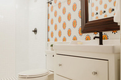 Inspiration for a mid-sized modern master wet room bathroom in Dallas with furniture-like cabinets, white cabinets, a one-piece toilet, white tile, ceramic tile, orange walls, ceramic floors, black floor, an open shower and white benchtops.
